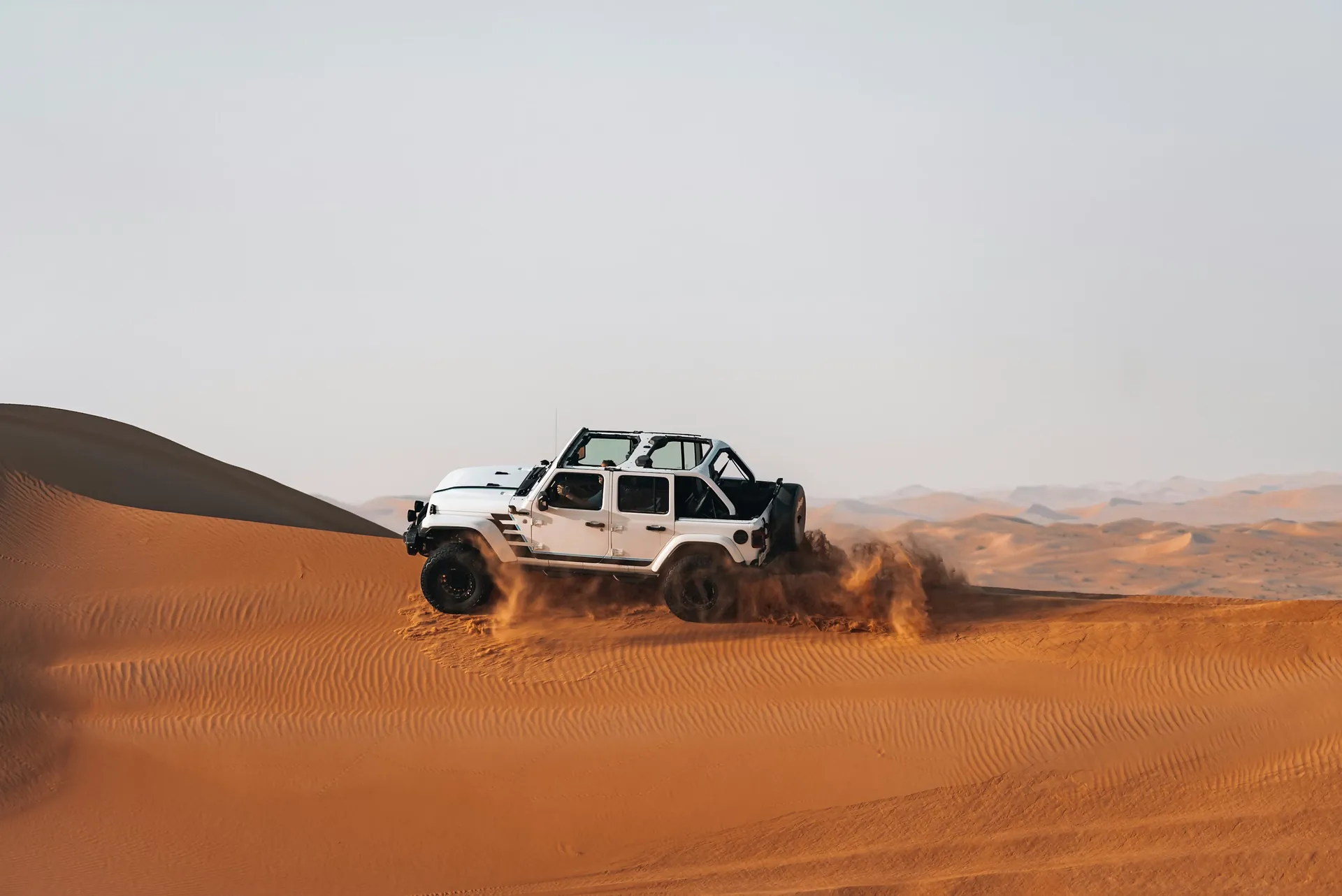 White off-road car on a sand dune in the desert